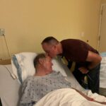 Man kissing his elderly father in hospital bed in hospital