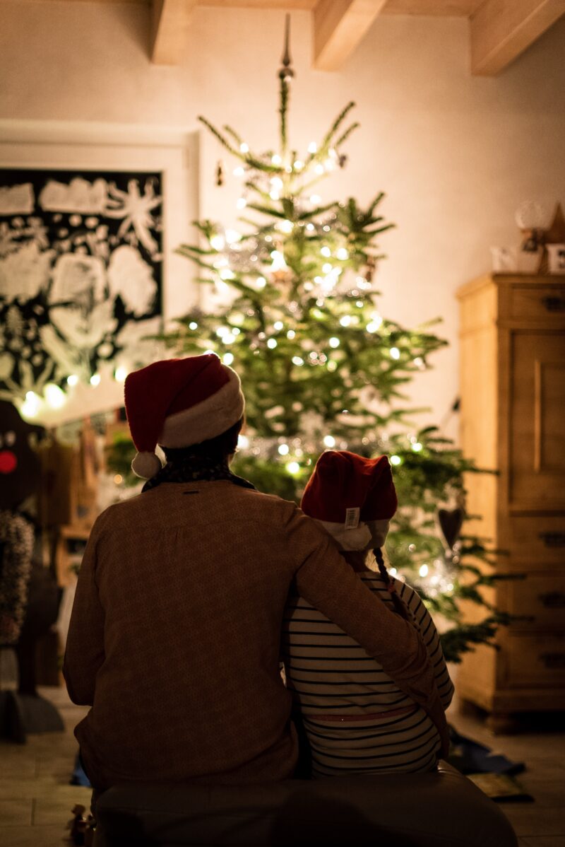 Father and child sitting in front of Christmas tree