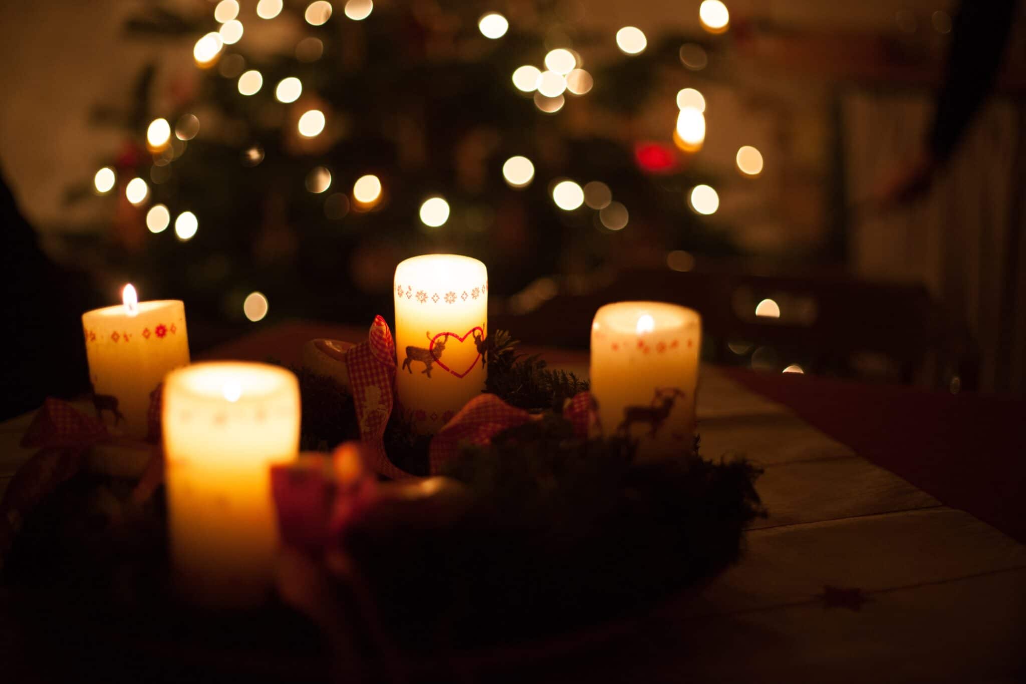 Advent candles lit in front of Christmas tree