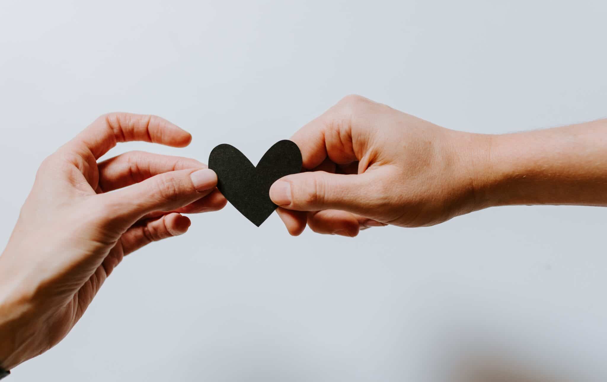 Two hand holding black paper heart