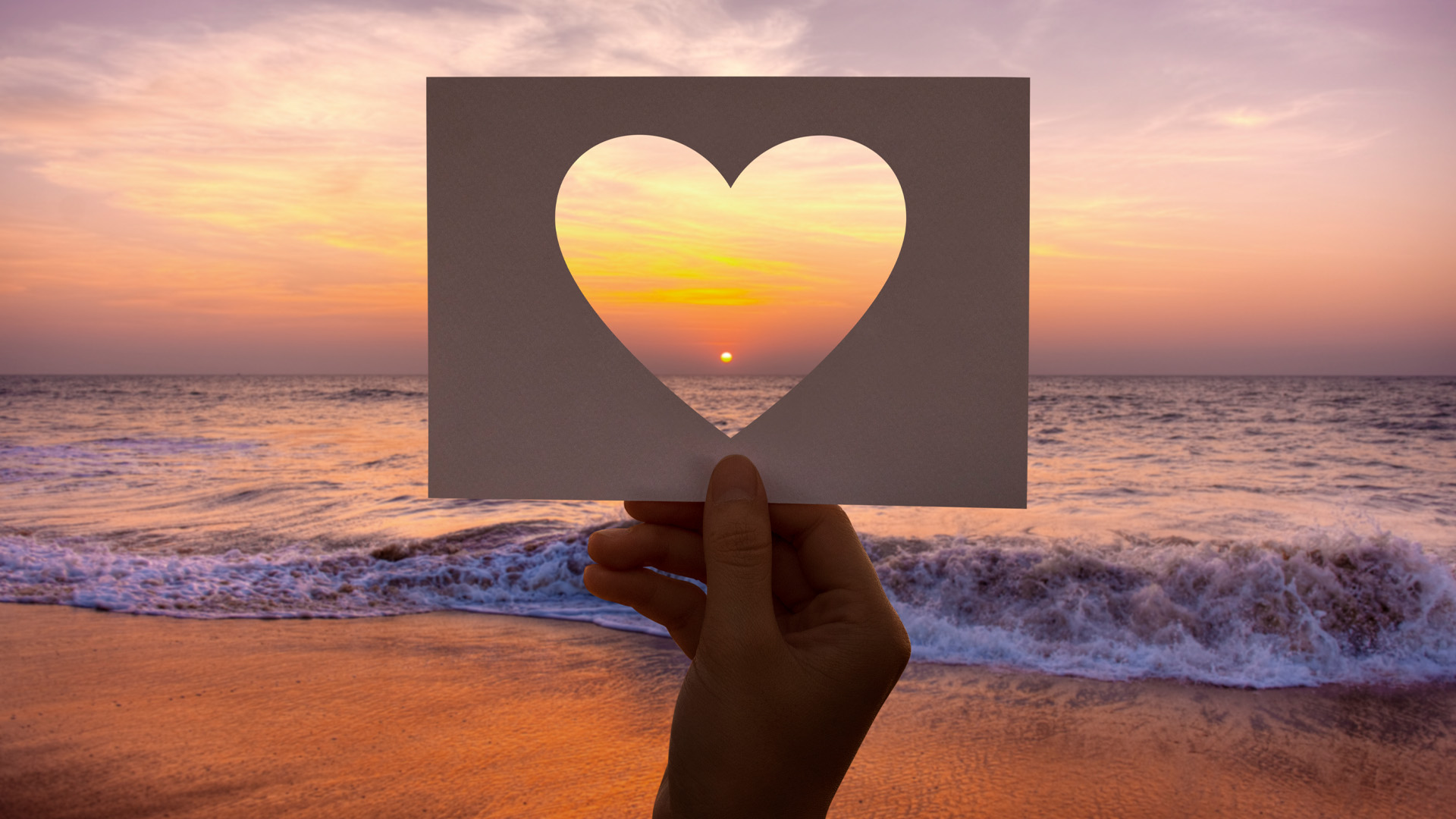Cutout heart with sunset and ocean in background.