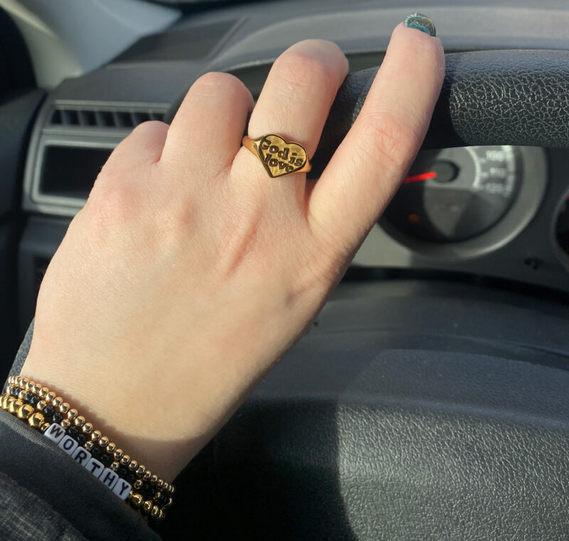 Ladies hand with a gold ring that says "God Is Love".