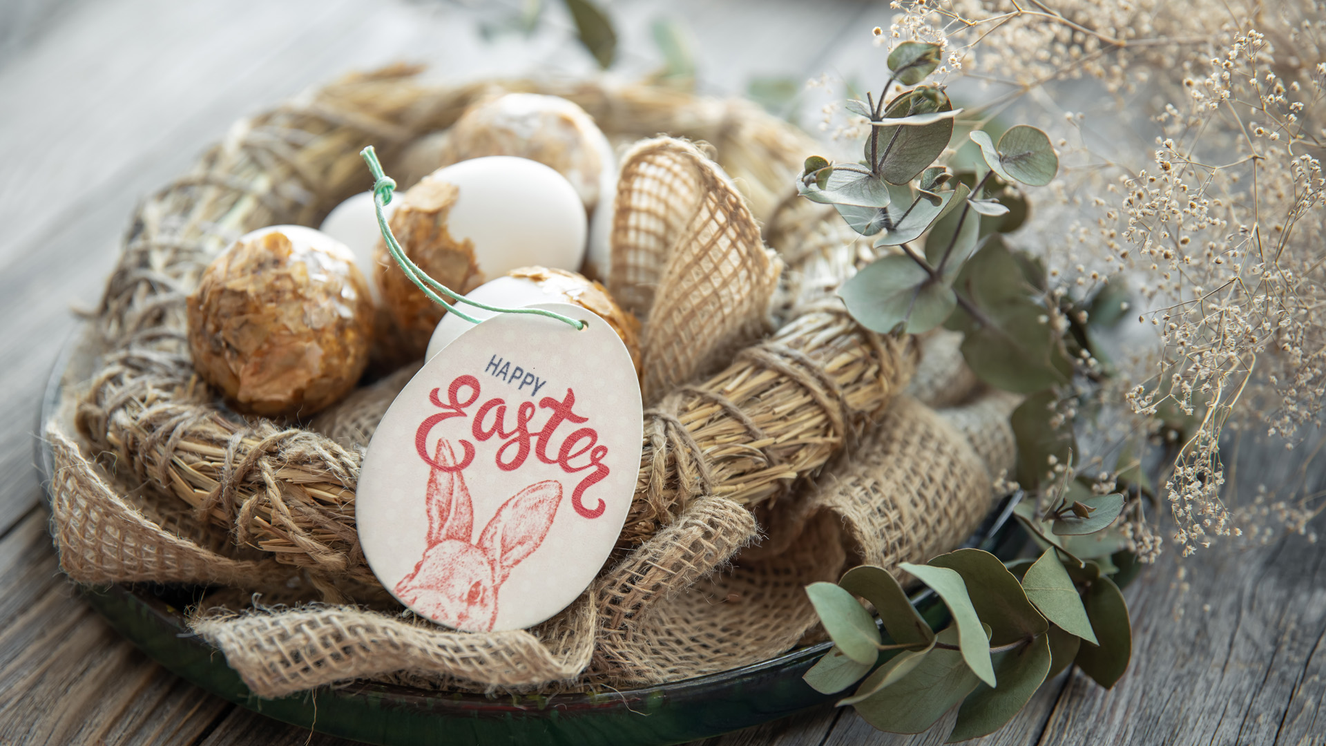 Tan fabric wreath on table with greens and easter tag.