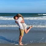 Pamela and her husband hugging on the beach.