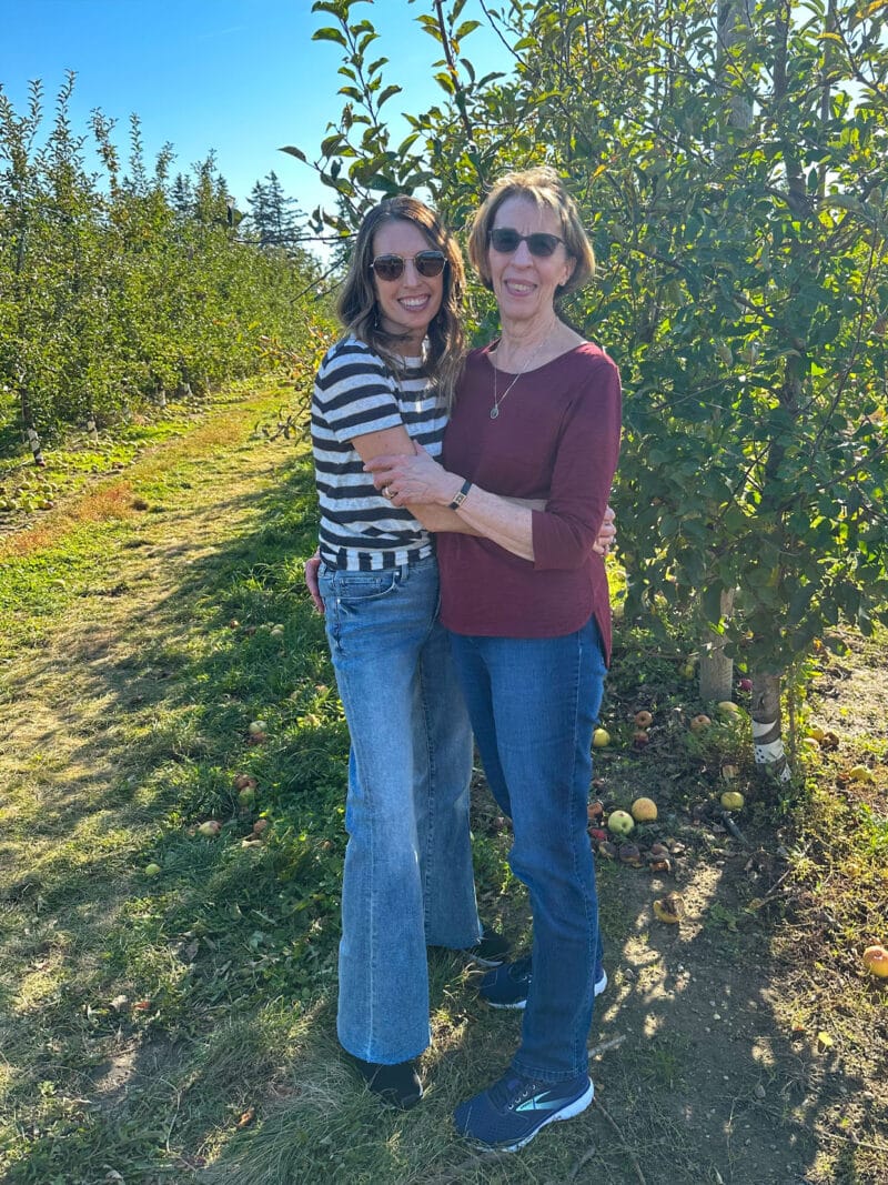 Adult lady and her mom hugging at apple orchard.