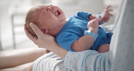 Alicia with newborn crying in her lap.