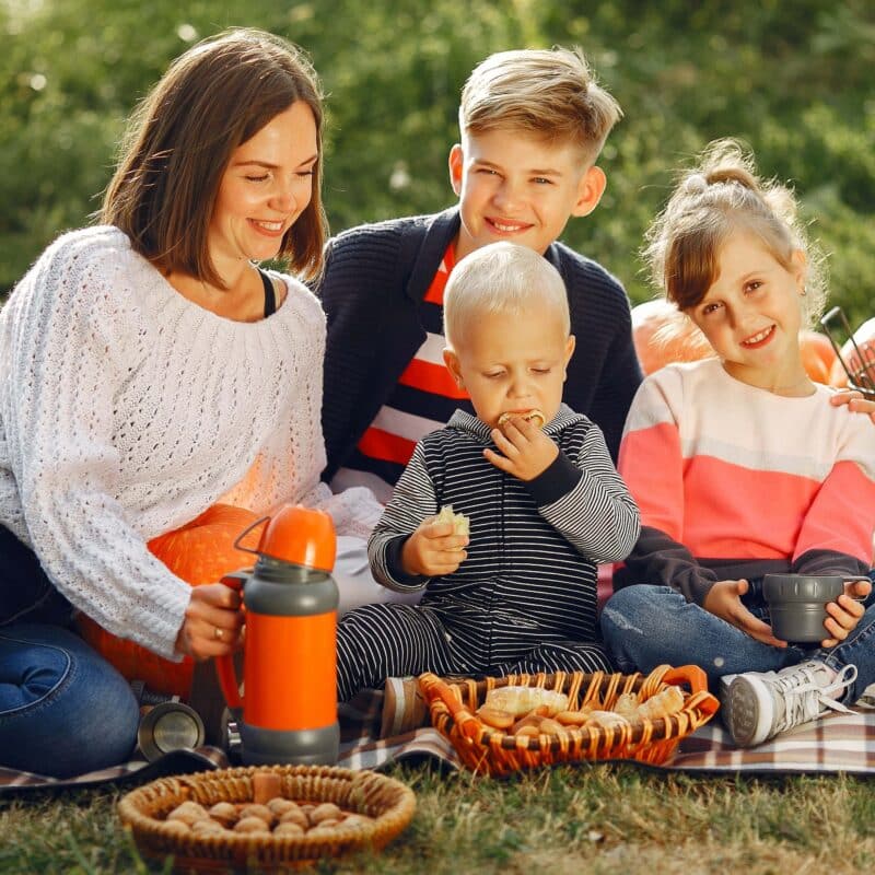 Family having fall theme picnic on the grass.