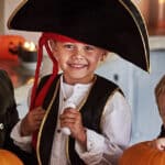 Family decorating pumpkins for Halloween with boy in a pirate hat.