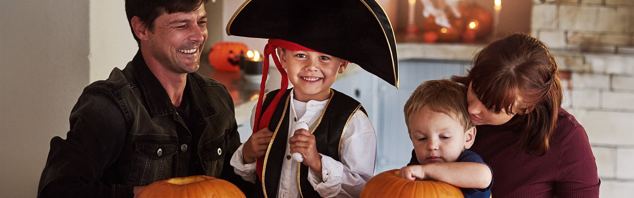 Family decorating pumpkins for Halloween with boy in a pirate hat.