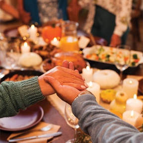 Family holding hands and saying Thanksgiving prayer.